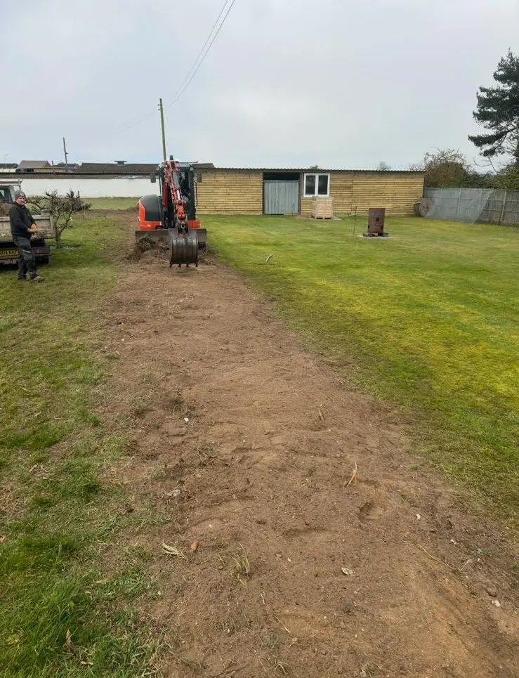 Mini excavator preparing garden pathway with freshly excavated soil