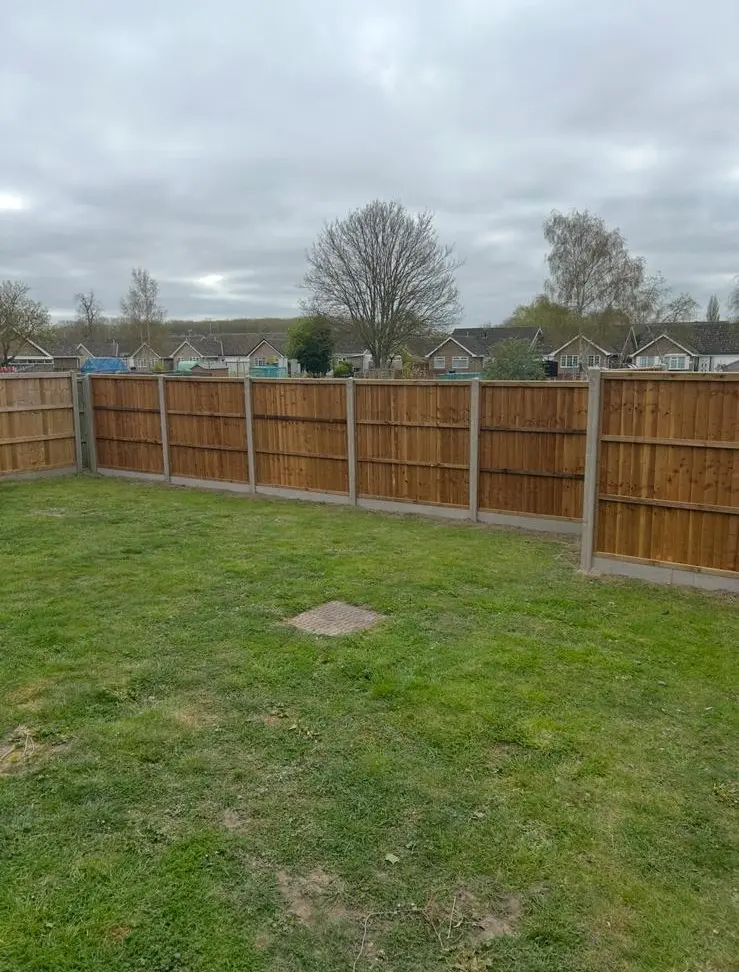 Horizontal lap panel fencing with concrete posts along garden boundary