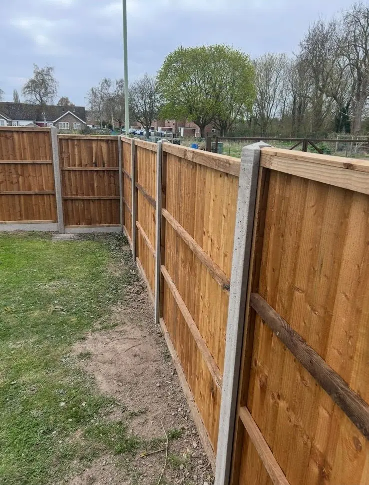 Close-up of featherboard fence panels with horizontal support rails and concrete posts