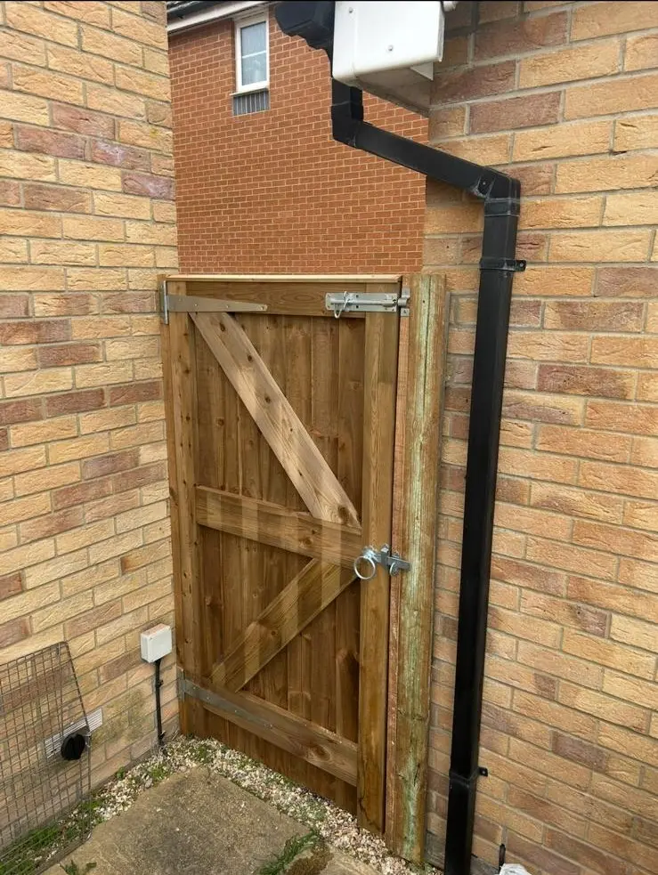 Sturdy wooden side gate fitted between two brick walls with a metal latch and support bracing